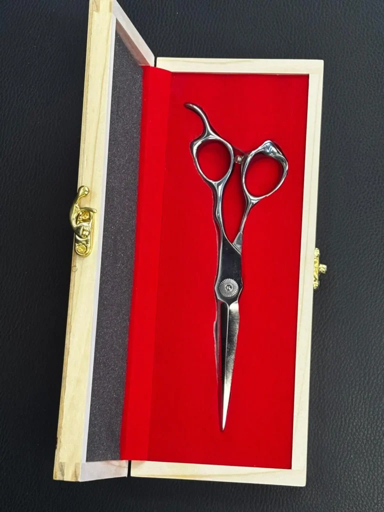 High-precision detail hair cutting scissors resting on a dark background shelf at Straight 8 Barbershop.